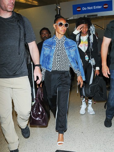 Jada Pinkett Smith’s travel style…blue denim jacket worn over a monochrome spot print shirt, black luxe joggers, white barely there sandals and a pair of white framed sunnies. Celebrity airport outfits | star style fashion