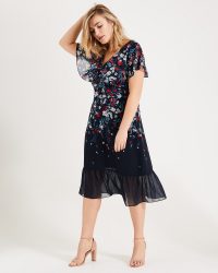 IMOGEN FLORAL PRINT DRESS | Studio8 | A stunning occasion style designed with a flattering fitted wrap bodice and a satin woven lining. Completed with a contemporary semi-sheer peplum hem and overlay sleeves