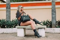 Black and white polka-dot shirt with black short shorts holding a black leather tote bag