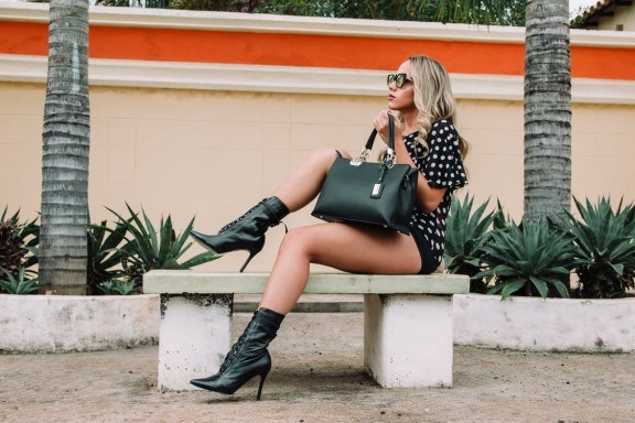 Black and white polka-dot shirt with black short shorts holding a black leather tote bag - flipped