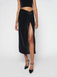 Reformation Nova Velvet Skirt in Black – glamorous wrap style evening midi skirts – luxe party fashion – thigh high slit hem – occasion glamour – gathered buckle detail