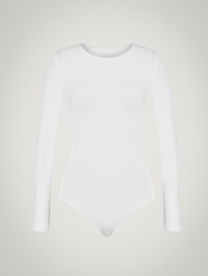 Selena Gomez’s white long sleeved crew neck bodysuit, Wolford BERLIN BODY. Worn with a selection of silver organic shaped bangles and drop earrings. For the cover of Rolling Stone, December 2022 issue | celebrity photoshoot outfits | star style fashion | minimalist bodysuits - flipped