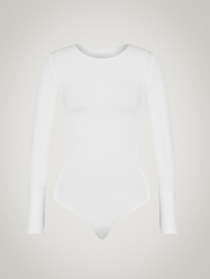 Selena Gomez’s white long sleeved crew neck bodysuit, Wolford BERLIN BODY. Worn with a selection of silver organic shaped bangles and drop earrings. For the cover of Rolling Stone, December 2022 issue | celebrity photoshoot outfits | star style fashion | minimalist bodysuits