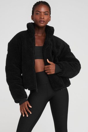 Addison Rae black zip up fleece, alo yoga SHERPA SNOW ANGEL PUFFER. Worn with black shorts, white over the knee socks, a pair of UGG slippers and carrying a small black nylon shoulder back by Prada. Out in Los Angeles, 11 November 2022 | casual celebrity street style | faux shearling fur jackets - flipped