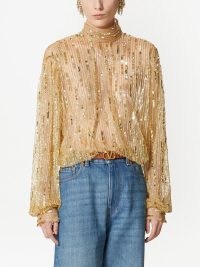 Nicky Hilton Rothchild’s gold sequinned high neck semi sheer top, Valentino Tulle Illusione sequin-embroidered blouse. Worn with a pair of blue denim flares and brown ankle strap platforms. On Instagram, 22 December 2022 | celebrity tops | social media fashion
