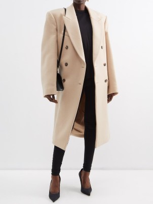 Rosie Huntington-Whiteley’s beige oversized longline coat, WARDROBE.NYC X Hailey Bieber double-breasted wool coat. Worn with a black hoodie and a pair of joggers, white trainers, a baseball cap and carrying a large quilted shopper bag. Out in London, March 2023 | celebrity street style coats | models off duty clothing - flipped